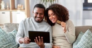 couple on couch with credit card and tablet ready to purchase services online