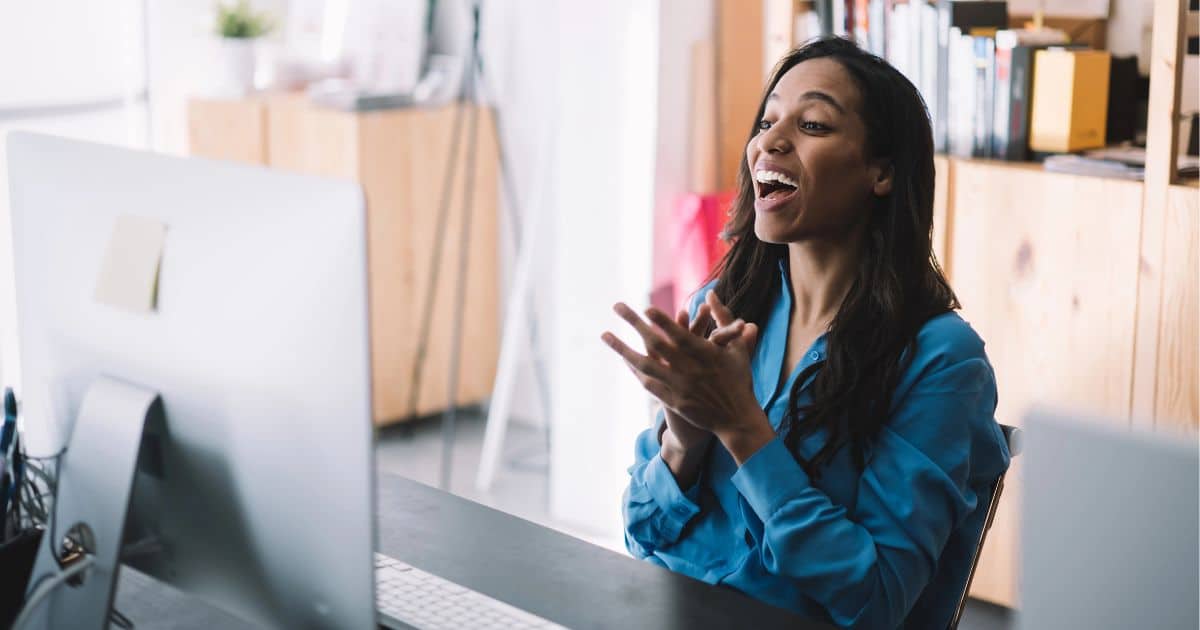 excited woman at her computer upon discovering her dream doula business name idea