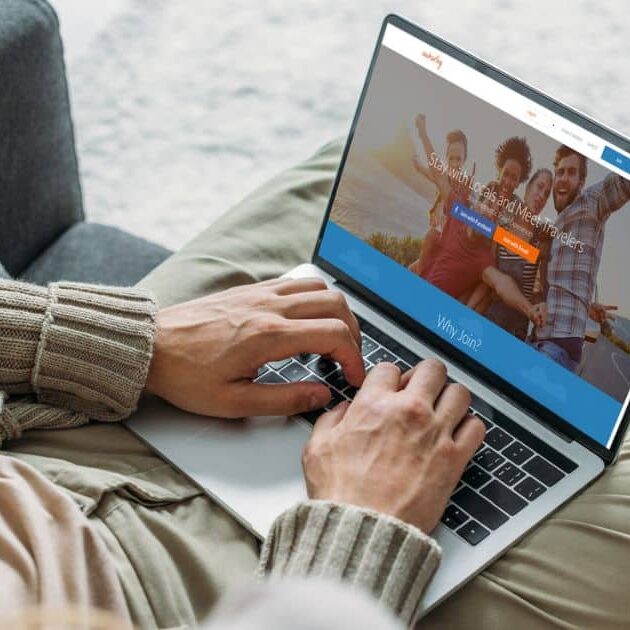 Person sitting comfortably at home browsing a travel website on their laptop, which displays images of happy travelers