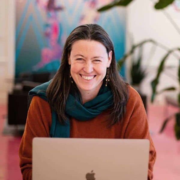Sarah Juliusson, The Website Doula, sits at her laptop in a colorful office.